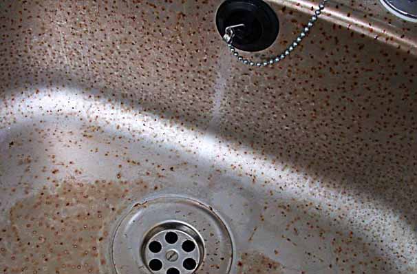 Cleaning fluid damage to a stainless steel sink unit.